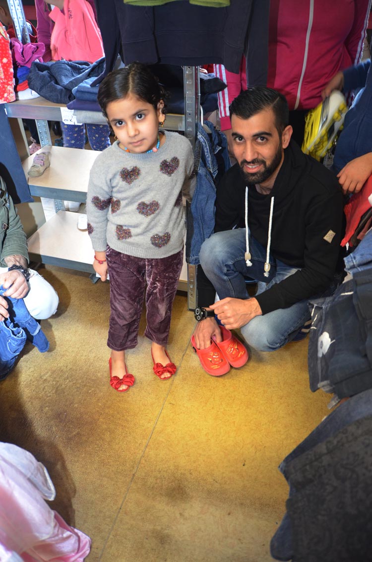 Zusammen mit ihrem Vater hat dieses kleine Flüchtlingsmädchen ein paar rote Schuhe entdeckt und ist glücklich.