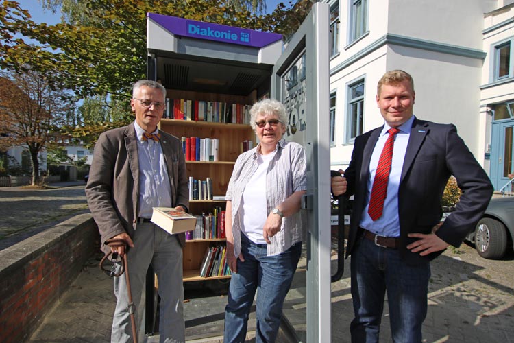 Diakonie-Vorstand Uwe K. Kollmann, Anwohnerin Ulla Meyer und Vorstandsassistent Benjamin Wehage übergeben die Bücherbox ihrer Bestimmung.