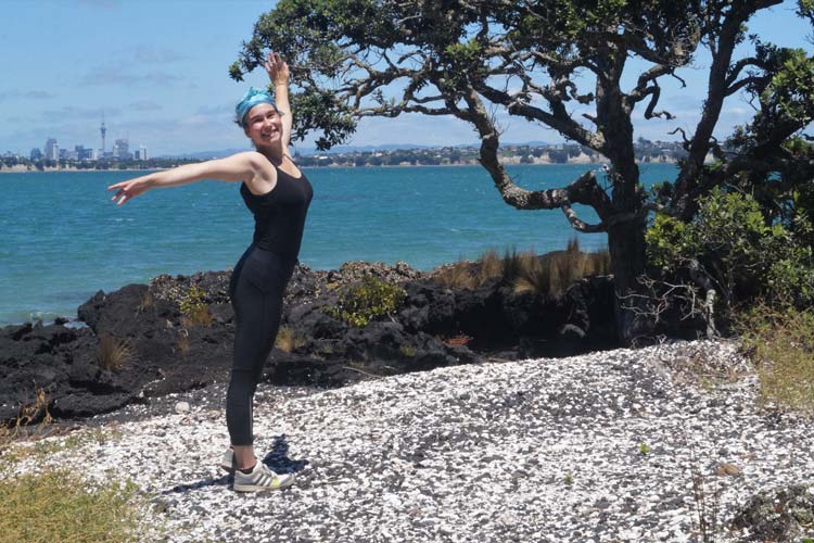 Danielle Zollickhofer auf Rangitoto Island, einer Vulkaninsel vor der Küste von Auckland. Links im Hintergrund ist die Skyline Aucklands zu sehen. Danielle Zollickhofer on Rangitoto Island, an ancient volcano in front of Auckland's shore. The skyline of Auckland can be seen on the left side of the picture.