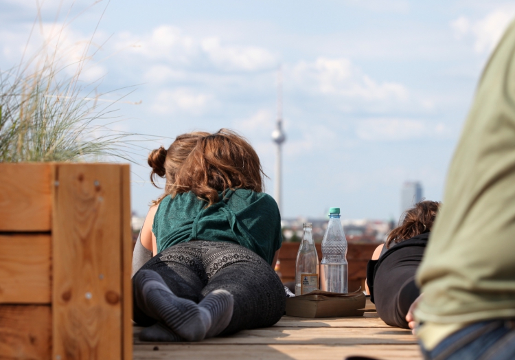 Junge Frau mit Getränken auf einer Dachterrasse mit Blick auf Berliner Fernsehturm, über dts Nachrichtenagentur