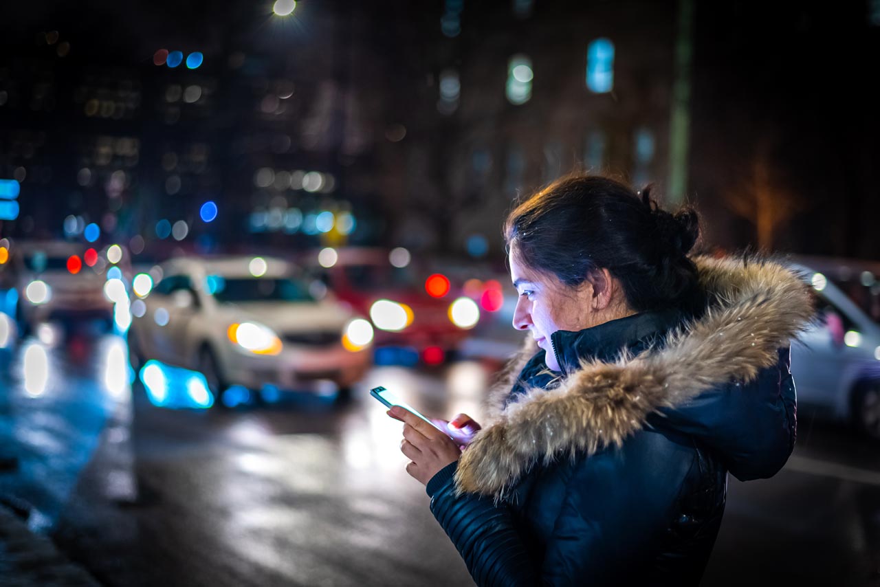 Eine Frau wartet in der Nacht auf ein Taxi.